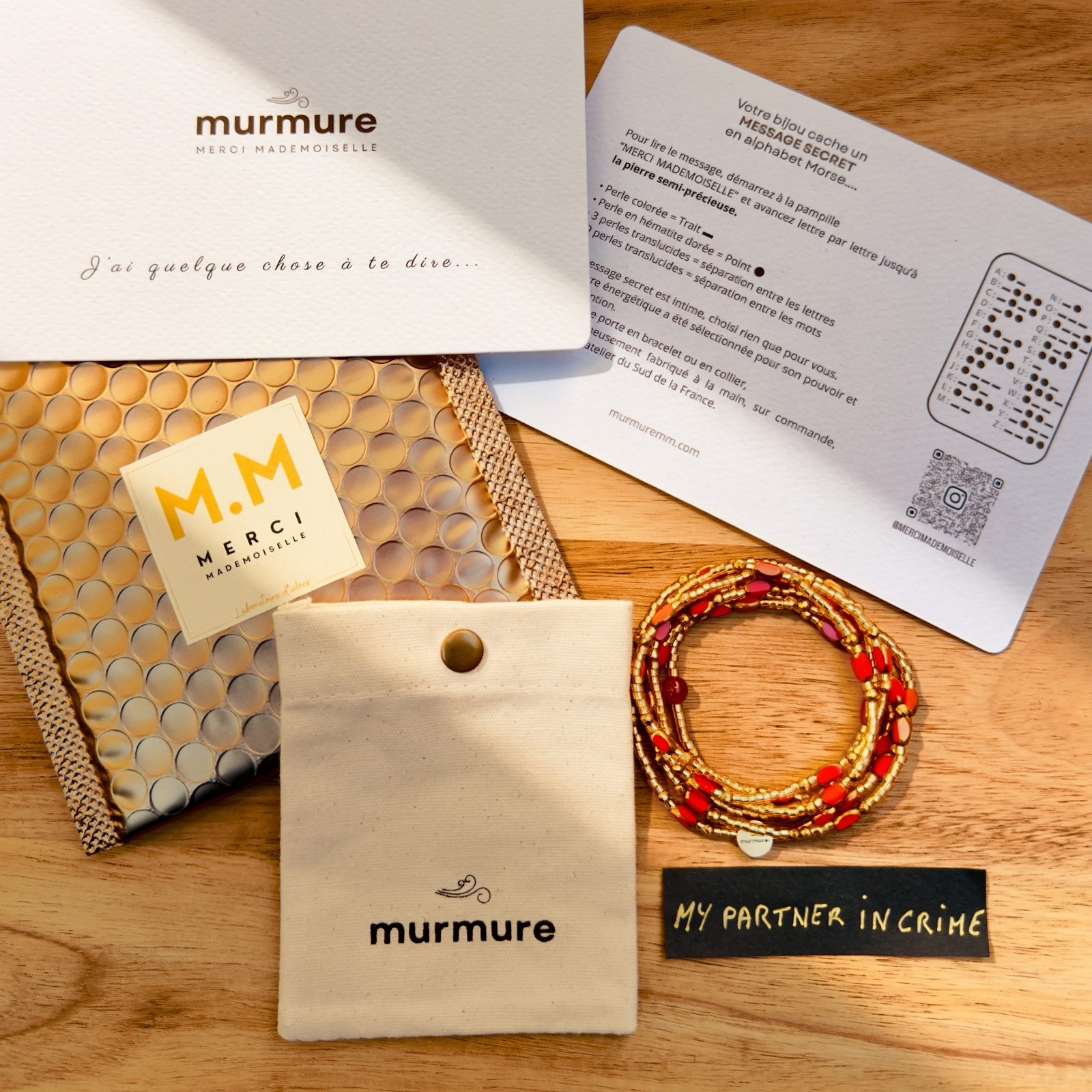 L'écrin Murmure complet : enveloppe dorée, carte, pochette en coton, bracelet et son message secret